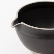 Close-up of black ceramic matcha bowl with pouring spout, designed for smooth tea preparation and easy serving.