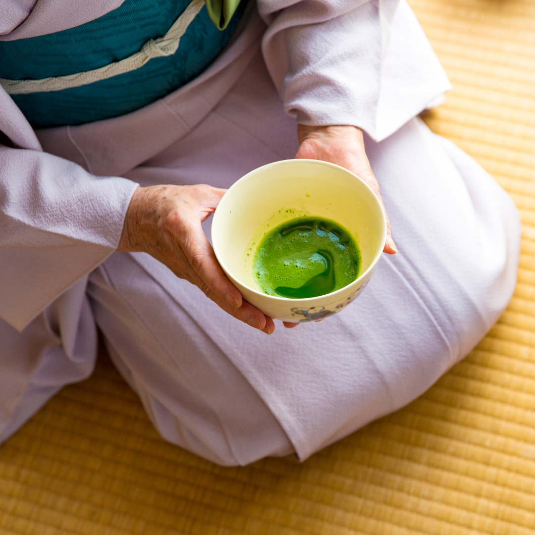 Lady dressed in traditional Japanese clothing holding a bowl of matcha tea