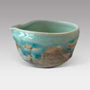 Handmade Japanese matcha chawan with flowing blue glaze and rustic ceramic body, featuring a subtle pouring spout