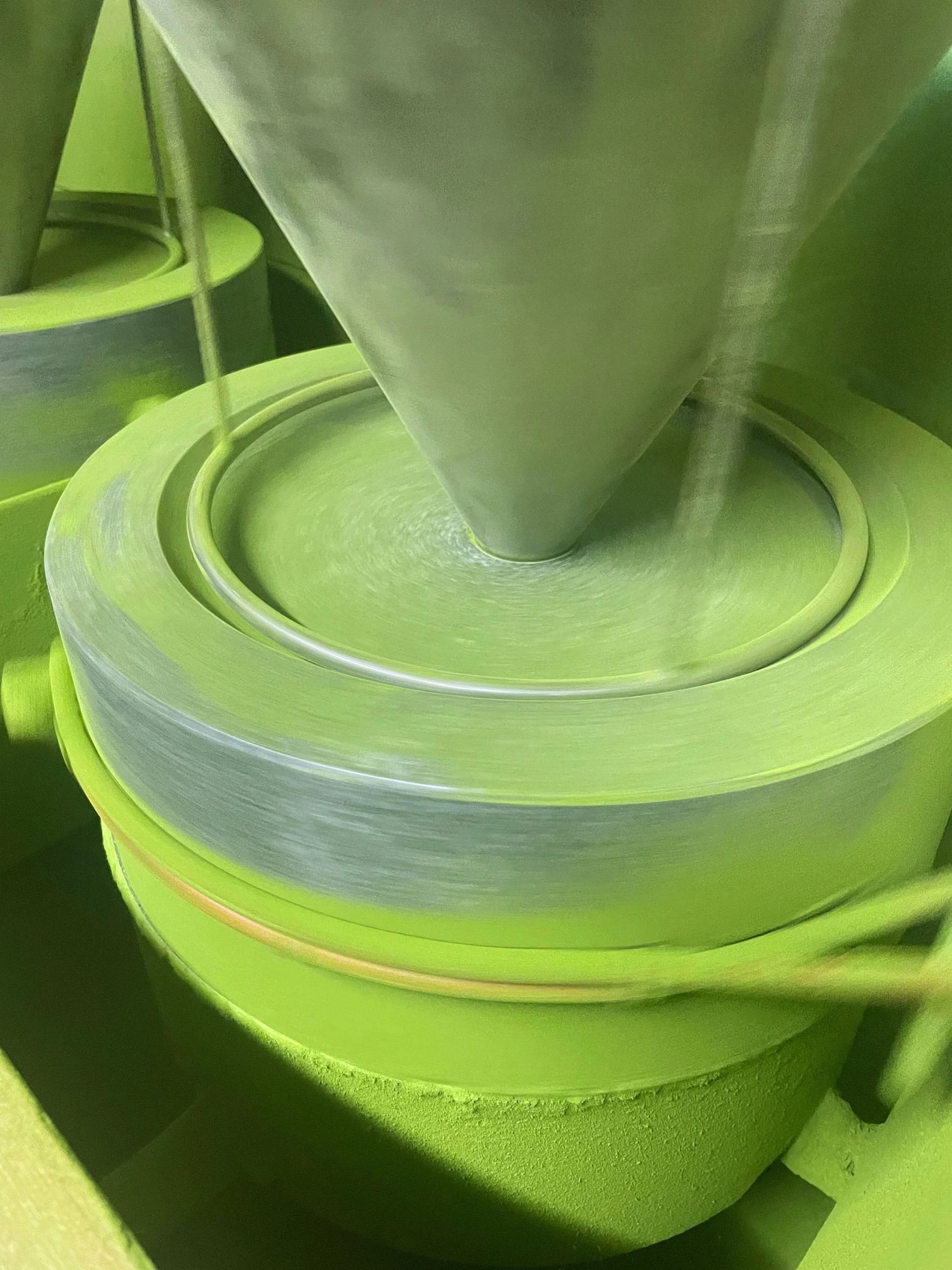 Traditional stone mill grinding Goko × Samidori tencha into fine Uji matcha powder, close-up action shot.