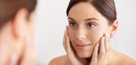 Woman checking her skin in a bathroom mirror