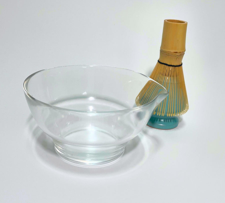 Glass matcha bowl with spout alongside bamboo chasen whisk resting on turquoise whisk holder