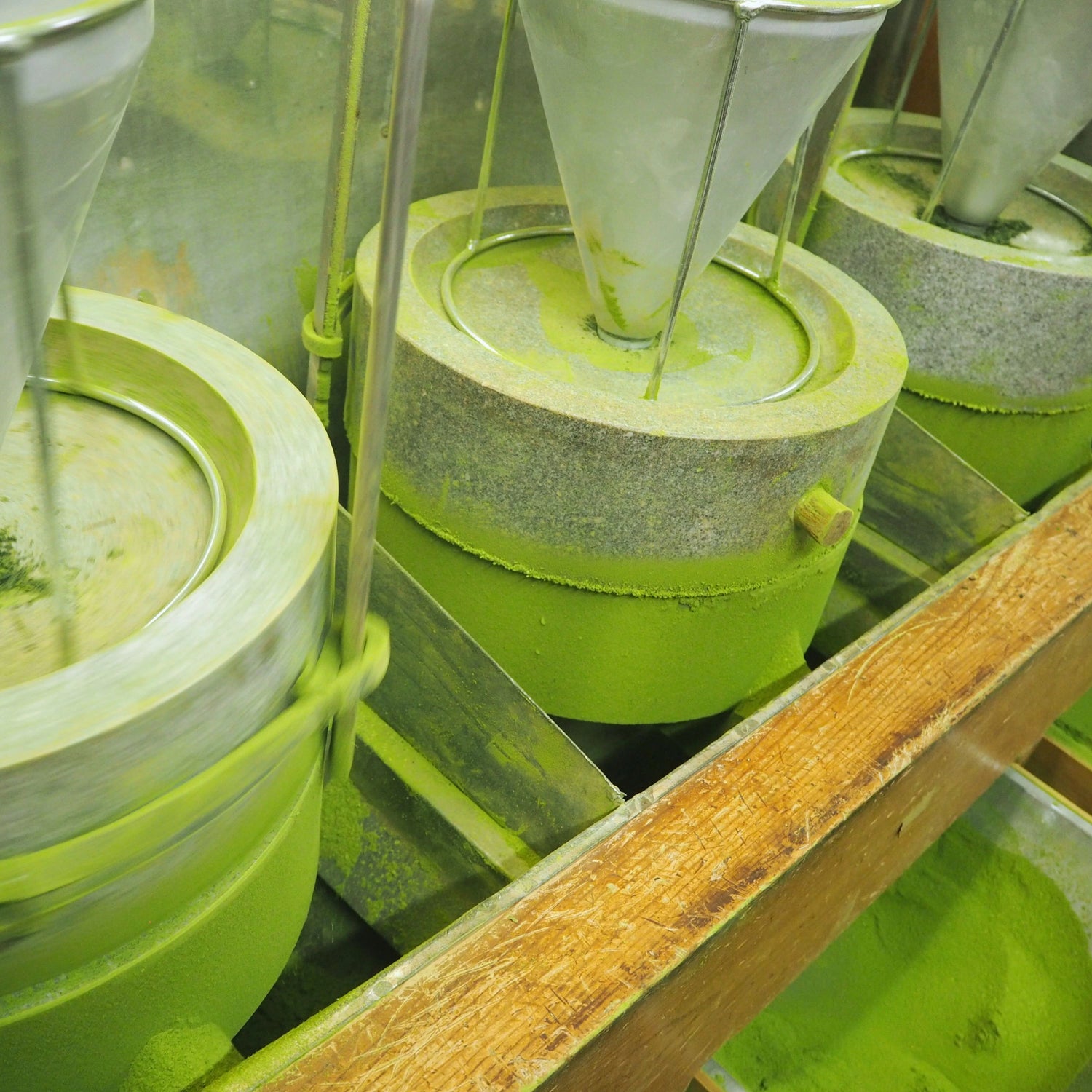 Traditional stone mills grinding Japanese matcha into fine powder at a processing facility in Kyoto.