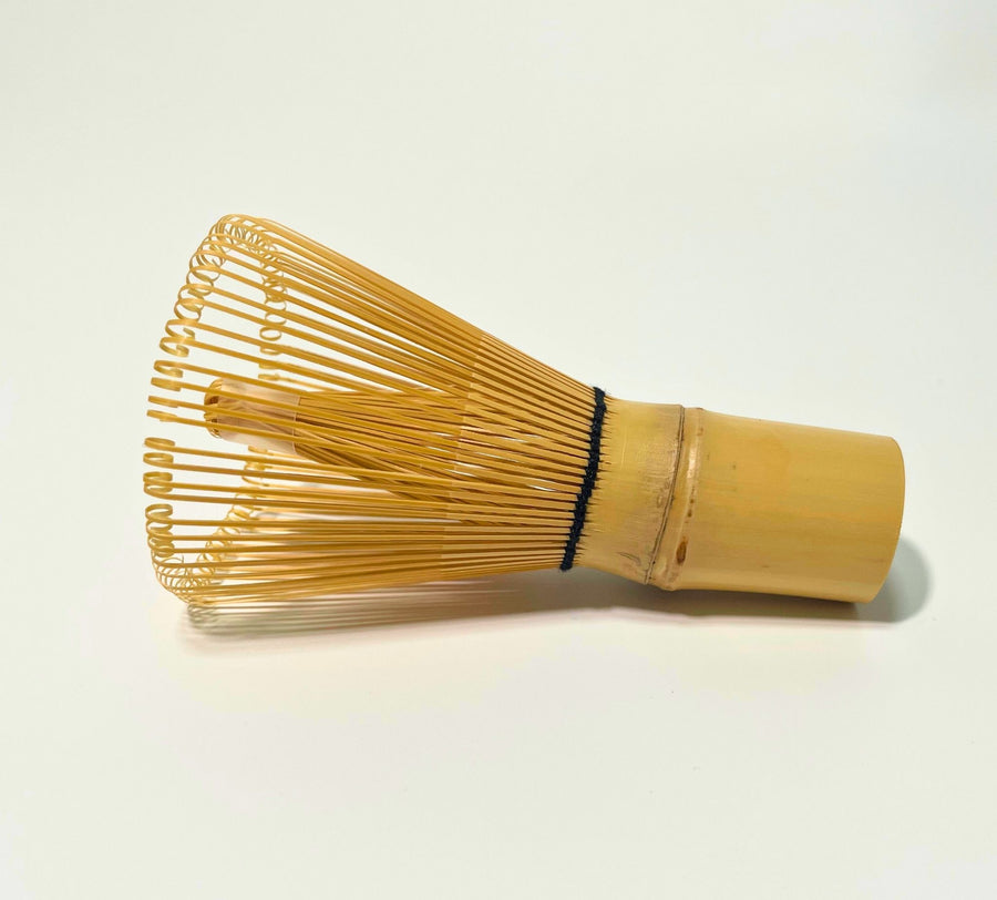 Side view of traditional 100-prong bamboo matcha whisk showing fine hand-carved loops and natural bamboo handle on white background
