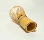 Rear angled view of 100-prong bamboo matcha whisk showing natural bamboo handle and fine prongs on white background