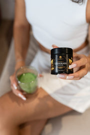 Woman sitting down holding a can of organic Ujihikari matcha green tea and a matcha latte in her opposite hand