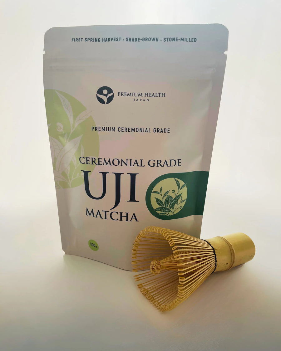 Ceremonial Grade Uji Matcha 100 g pouch with a bamboo chasen placed beside it, photographed in soft natural light.