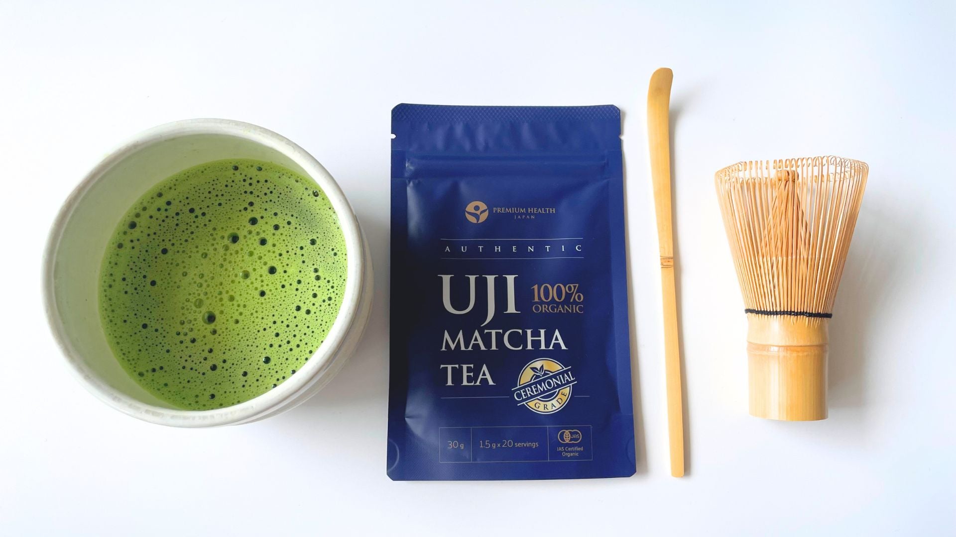 Matcha tea in a chawan, packet of ceremonial grade matcha, bamboo scoop and whisk