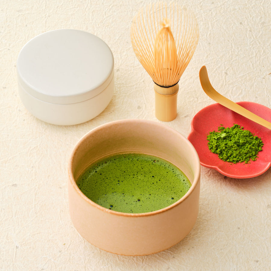 First Spring Harvest ceremonial Uji matcha 100g with bamboo whisk, chashaku scoop, vivid green matcha powder on a red plum-shaped dish and a whisked bowl
