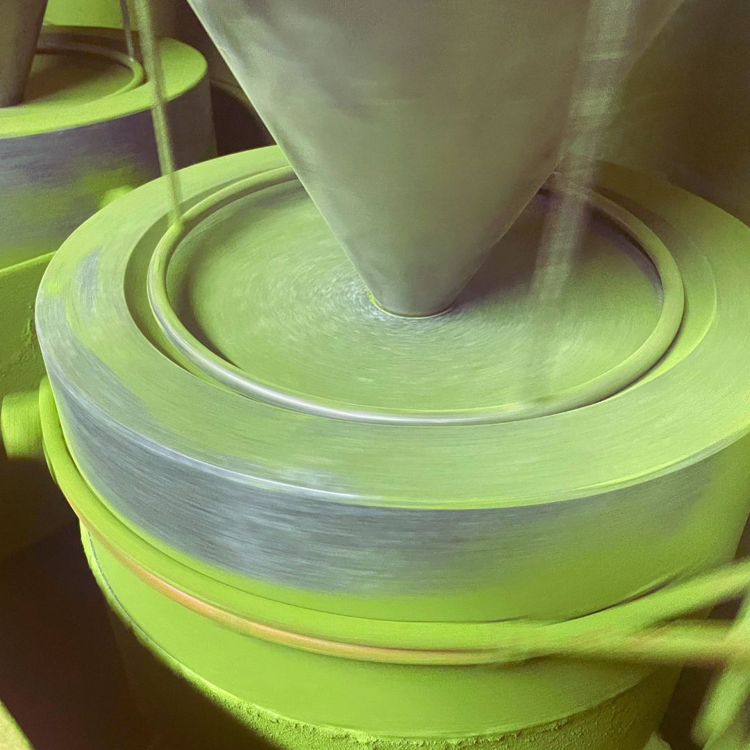 Close-up of traditional stone mill grinding tencha into fine matcha powder, creating high-quality Japanese green tea.