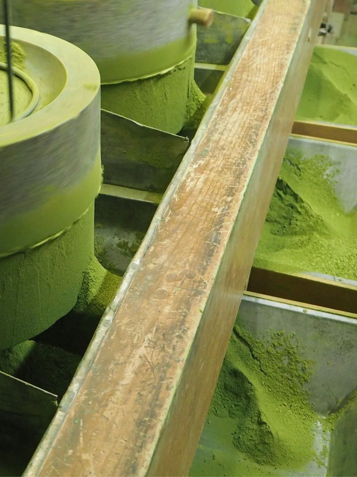 Traditional stone milling of Japanese matcha in Kyoto, producing a fine, vibrant green tea powder