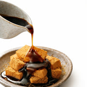 Okinawa kokuto black sugar syrup poured over warabi mochi dessert, rich Japanese brown sugar syrup for sweets and matcha pairing
