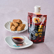 Okinawa brown sugar syrup (kokuto mitsu) 200g squeeze pouch beside a glass dish of dark syrup and a plate of raw Okinawan kokuto black sugar chunks
