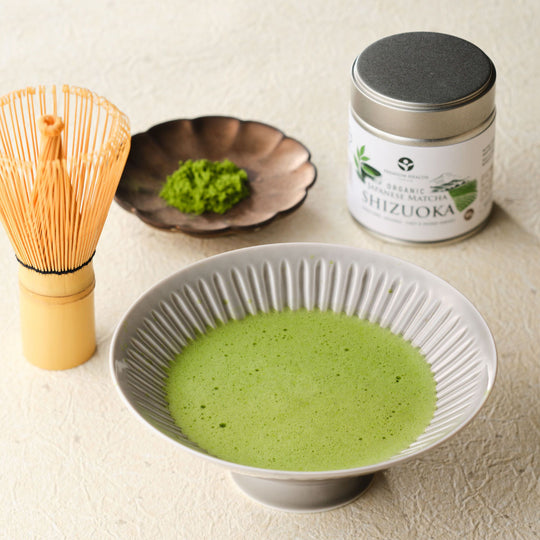 Bowl of freshly whisked usucha with a bamboo chasen, dish of matcha powder, and the Organic Japanese Matcha Shizuoka tin