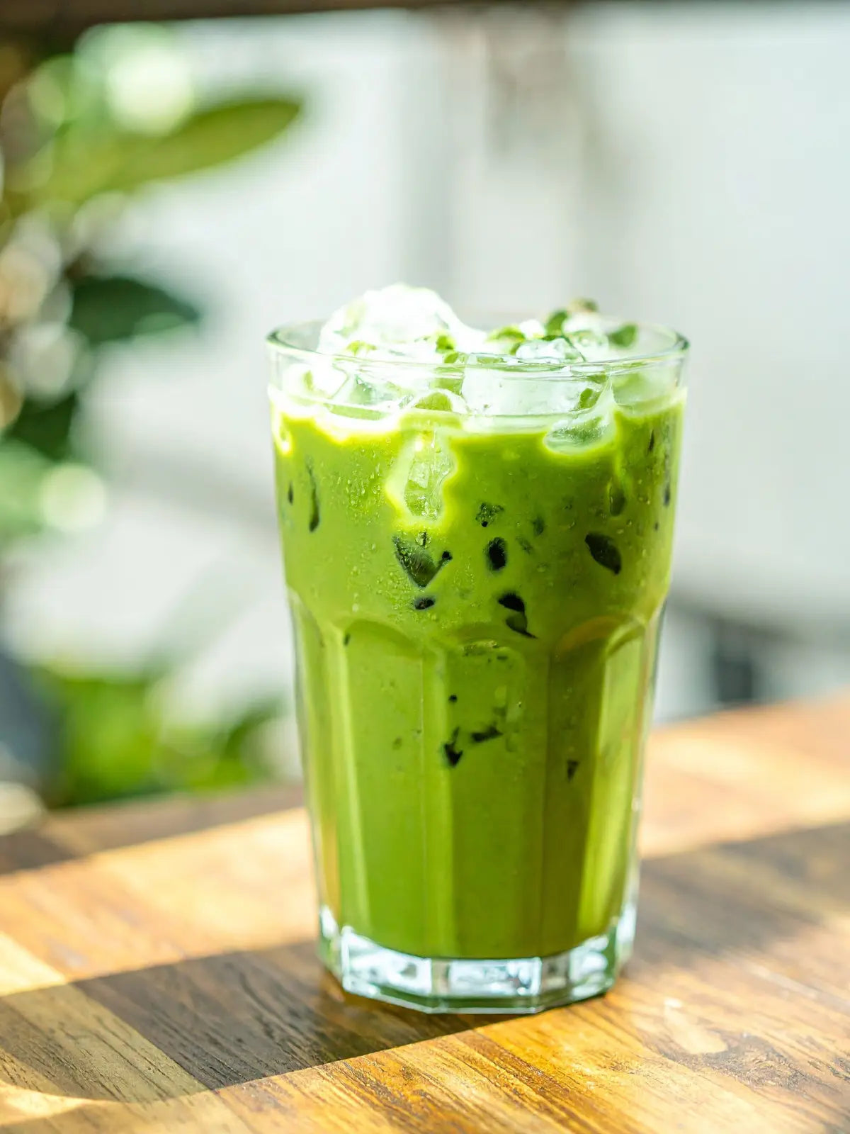 Iced latte made with organic Japanese matcha powder, showing a vibrant green colour and smooth, creamy texture in a clear glass.