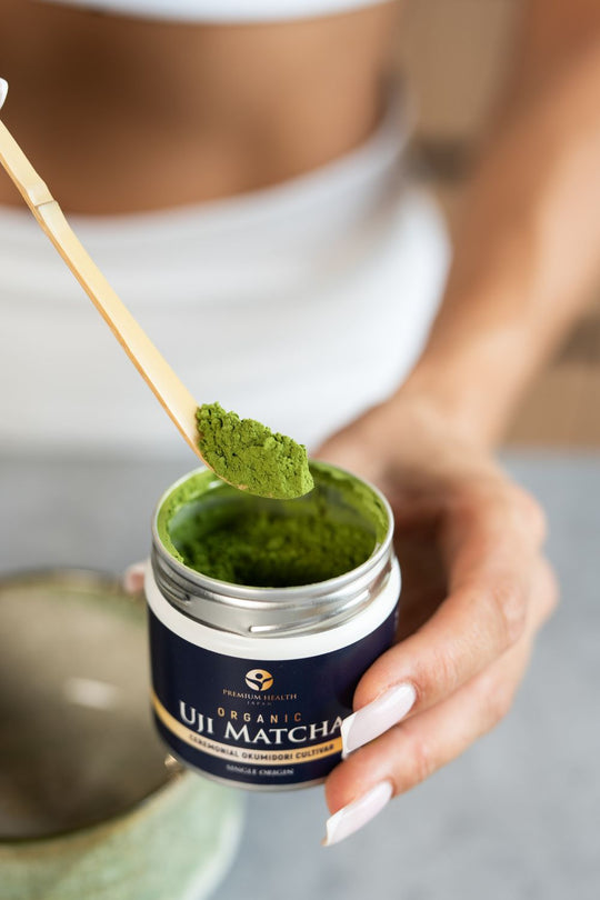Person holding a chashaku scoop of organic Okumidori Uji matcha above an open 30g tin.