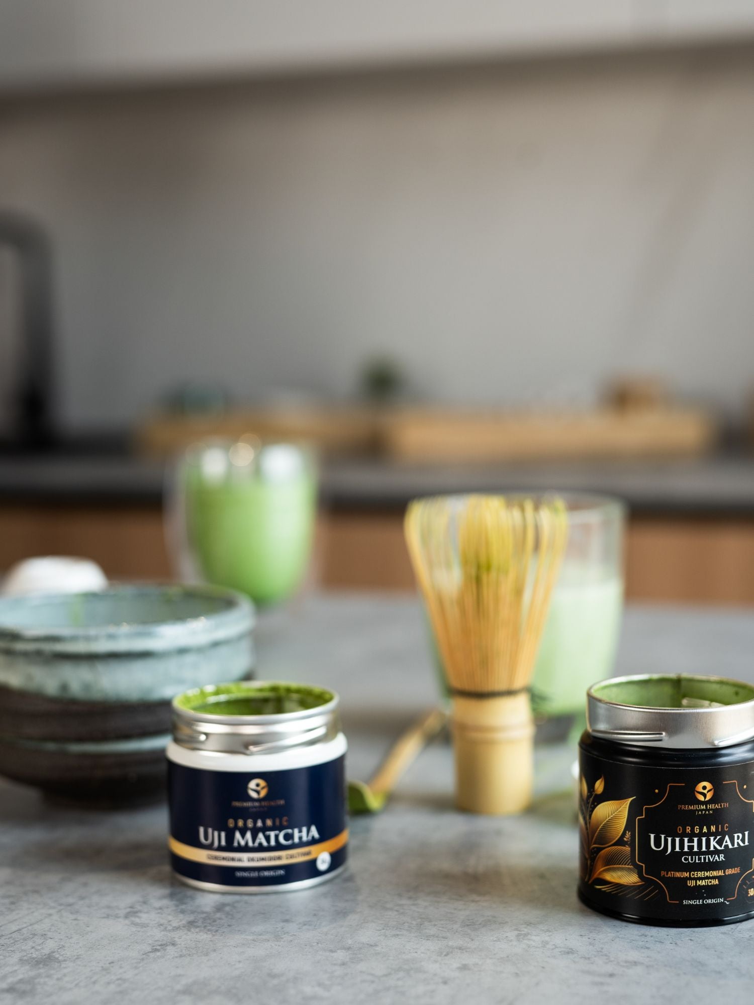 Product image showcasing organic matcha, chawan matcha bowl, and bamboo whisk, and matcha lattes in the background