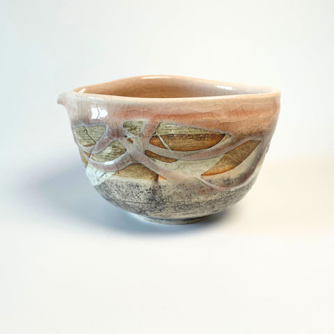 Side view of a Japanese Nagashi matcha bowl with spout, showcasing layered natural tones and an abstract textured design with pink and beige glaze accents.