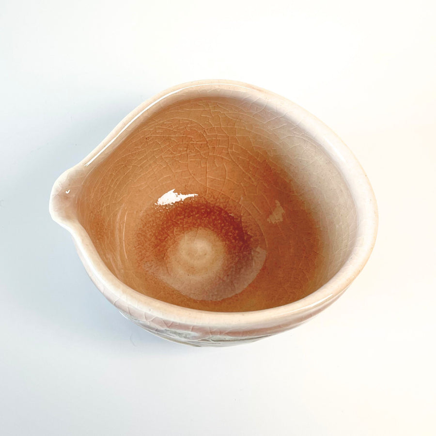 Top view of a handcrafted Nagashi matcha bowl with a pouring spout, featuring a warm, earthy pink glaze and fine crackle pattern inside the bowl.