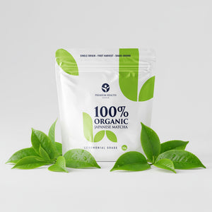 Organic Japanese matcha in a 50g pouch with fresh tea leaves on a white background, showcasing ceremonial grade packaging.