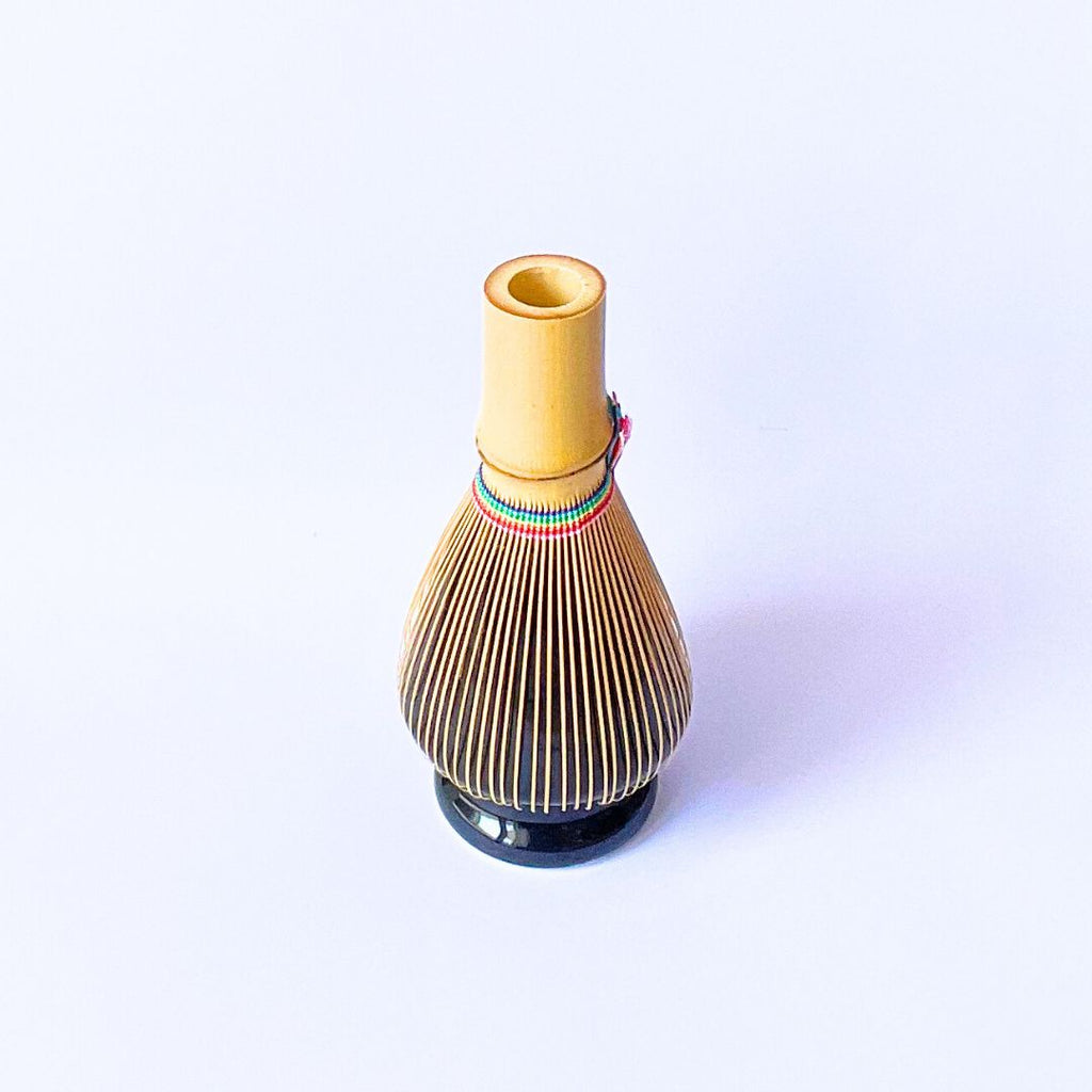 Bamboo matcha whisk resting on a ceramic kusenaoshi whisk holder from Suikaen Takayama, which preserves the whisk's curved shape