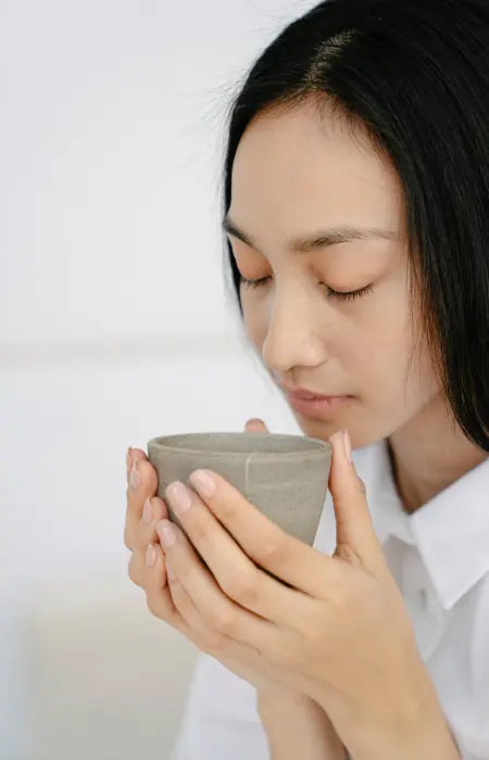 Person enjoying a traditional bowl of matcha, holding a ceramic tea bowl during a calm, mindful moment.