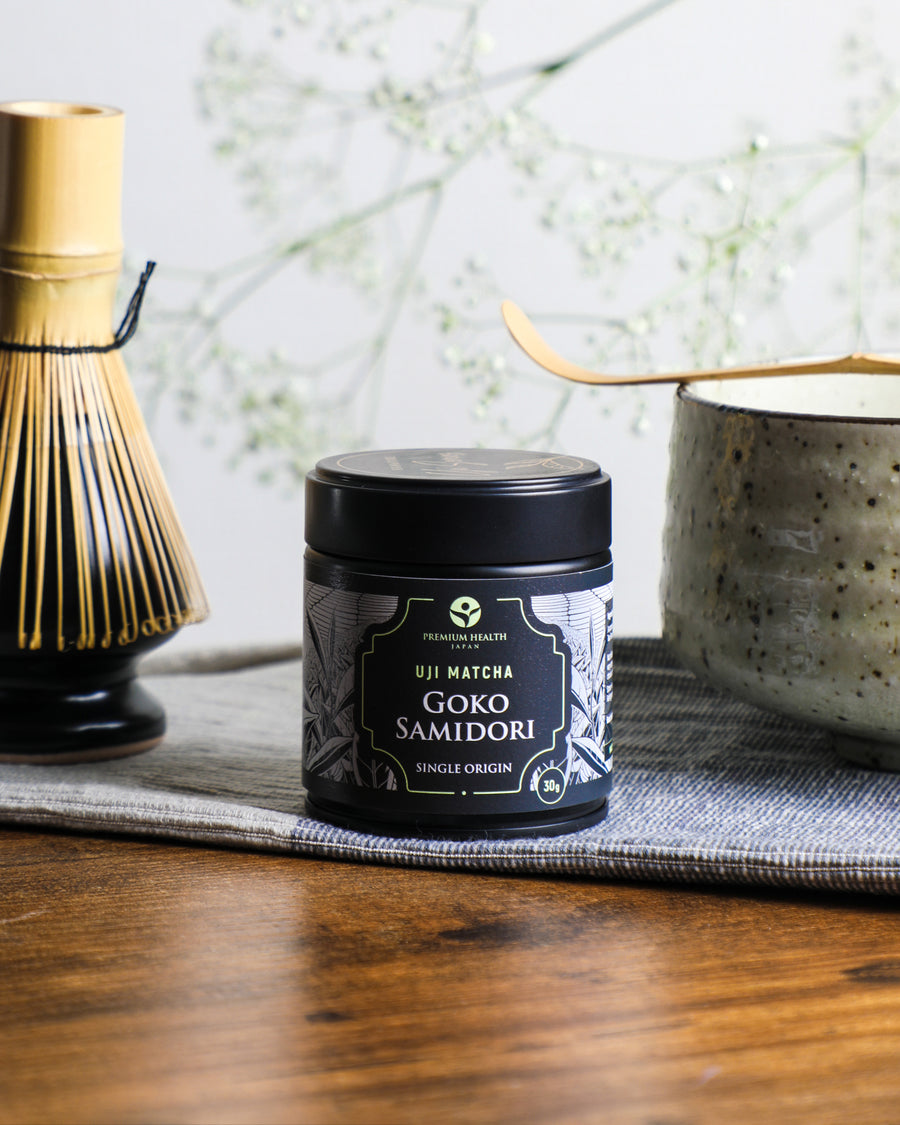 Premium Health Japan Uji Matcha Gokō Samidori 30g tin beside a bamboo whisk and chawan, showcasing authentic single-origin Kyoto matcha preparation.