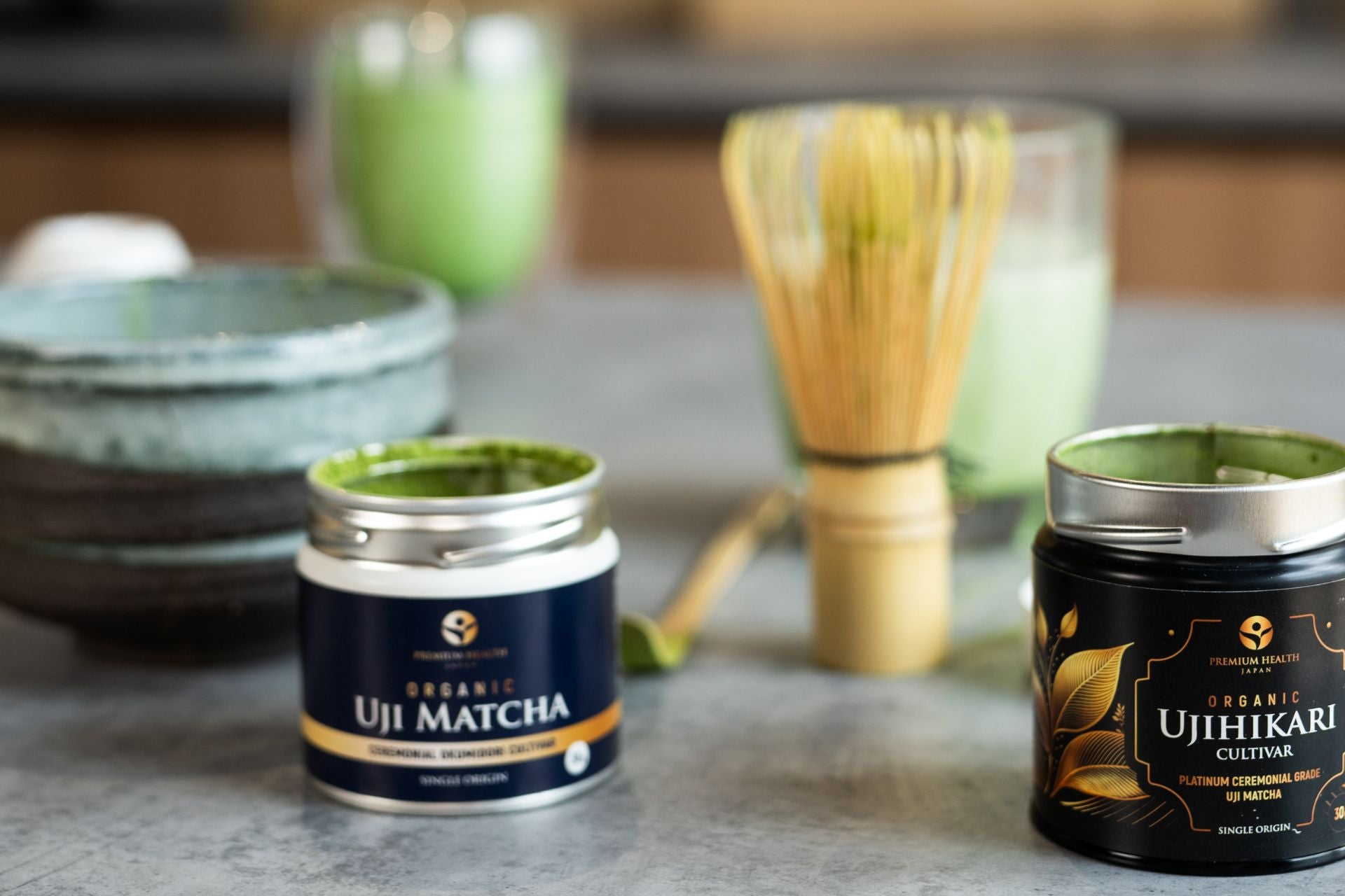 Product image showcasing organic matcha, chawan matcha bowl, and bamboo whisk, and matcha lattes in the background